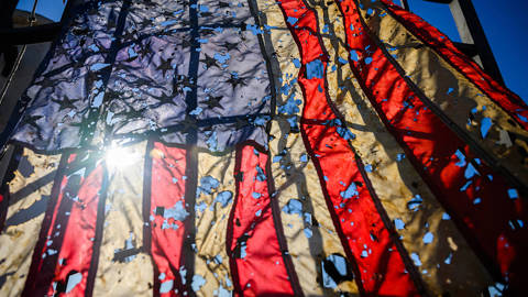 A torn American flag hanging from the doorway and debris scattered around the property.