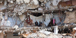 Displaced Palestinians sit outside makeshift shelters among the rubble of destroyed buildings in Jabalia refugee camp, northern Gaza Strip, highlighting ongoing humanitarian crisis and widespread destruction amid the Israel-Palestine conflict.
