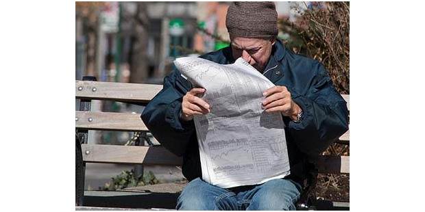 Man reading newspaper finance section
