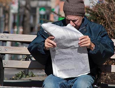 Man reading newspaper finance section