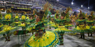 Performers of the Estação Primeira de Mangueira samba school parade in colorful costumes during the 2026 Rio Carnival in Rio de Janeiro, Brazil. They dance along the Sambadrome, accompanied by elaborate floats, as part of the Special Group competition judged to select the annual champion.