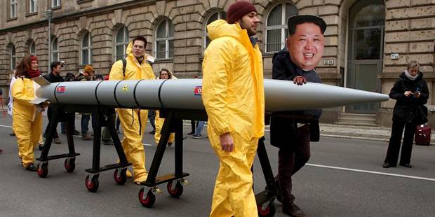  An activist with a mask of Kim Jong-un marches with a model of a nuclear rocket