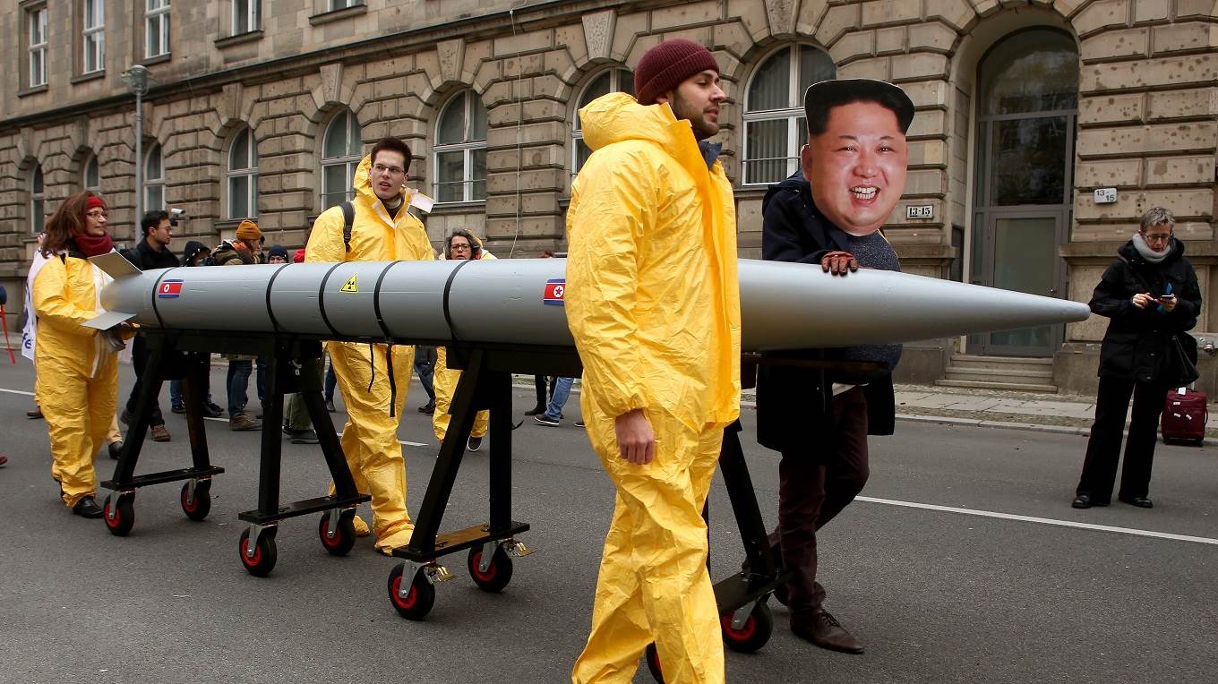 An activist with a mask of Kim Jong-un marches with a model of a nuclear rocket