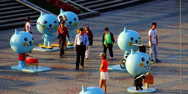 Crowd in China disinterested in large toy-cat installation.