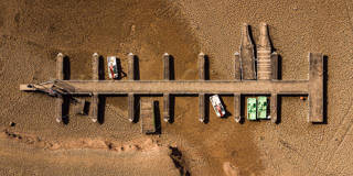 Pedal boats sit stranded on dry, cracked ground at the Sau Reservoir in Catalonia, Spain, as severe drought exposes the lakebed where water once covered the area.