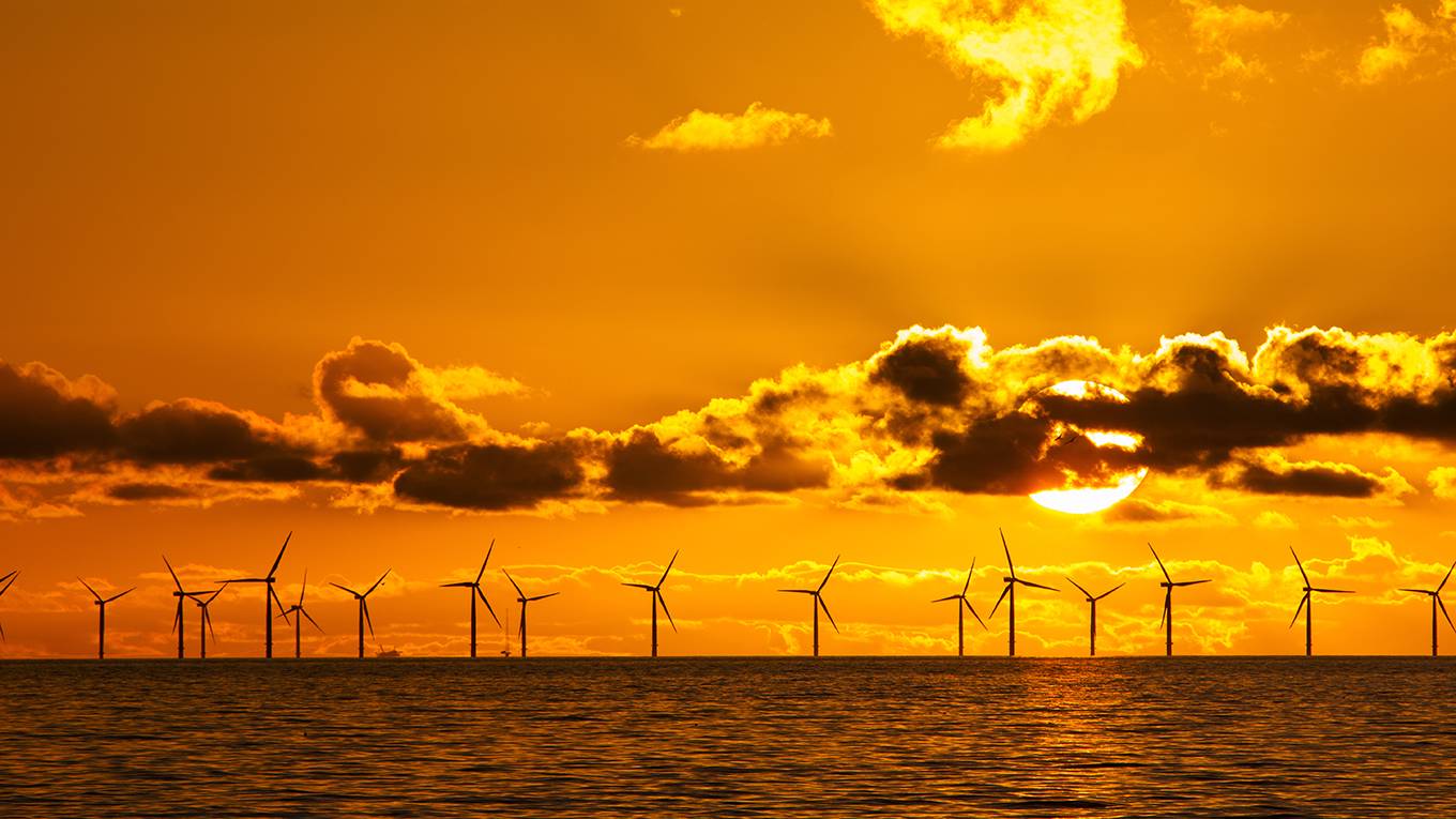 eman1_AshleyCooperBarcroftImagesBarcroftMediaviaGettyImages_sunsetoceanwindturbinesorange