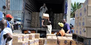 Men unload boxes of soap from a truck at the port of Abidjan