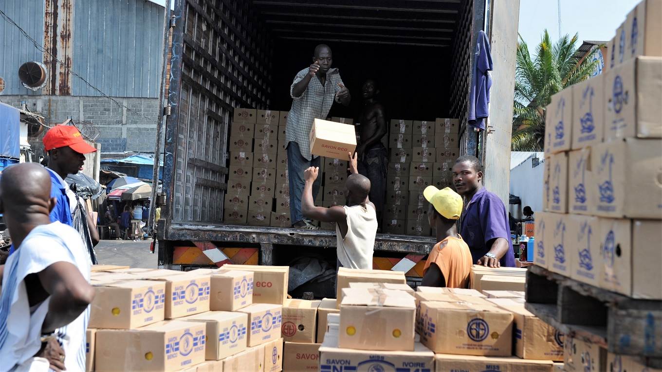 Men unload boxes of soap from a truck at the port of Abidjan