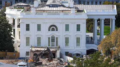 An excavator removes debris during demolition work at the White House East Wing site, where the former structure—associated with the planned White House ballroom—has been torn down, leaving piles of rubble and exposed foundations within the grounds of the U.S. presidential residence.