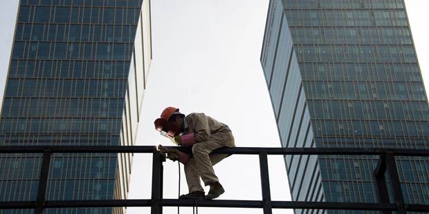 A worker welds a scaffolding in front of the headquarters of the Agricultural Bank of China