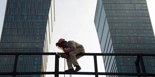 A worker welds a scaffolding in front of the headquarters of the Agricultural Bank of China