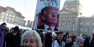 A woman holds a sign with a portrait of the US president during a protest against his planned visit to the World Economic Forum in Davos