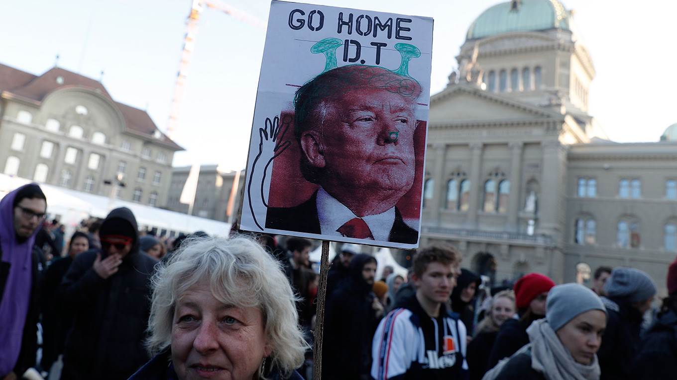 A woman holds a sign with a portrait of the US president during a protest against his planned visit to the World Economic Forum in Davos
