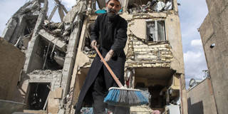 A man sweeps up debris near a residential building that was hit in an airstrike in the early hours of March 27, 2026 in Tehran, Iran.