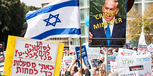 Israeli protesters raise a sign in Hebrew 'Mandelblit, let us decide, we came from Mahalot to protest', as they demonstrate against Prime Minister Benjamin Netanyahu