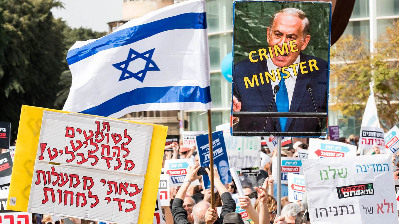 Israeli protesters raise a sign in Hebrew 'Mandelblit, let us decide, we came from Mahalot to protest', as they demonstrate against Prime Minister Benjamin Netanyahu