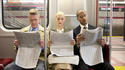 people reading the newspaper on the subway