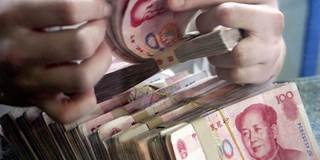 A bank teller counts Chinese currency 100 yuan (or Renminbi) notes 