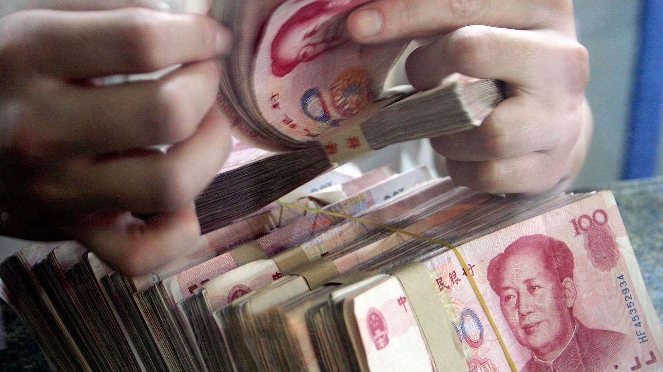 A bank teller counts Chinese currency 100 yuan (or Renminbi) notes 