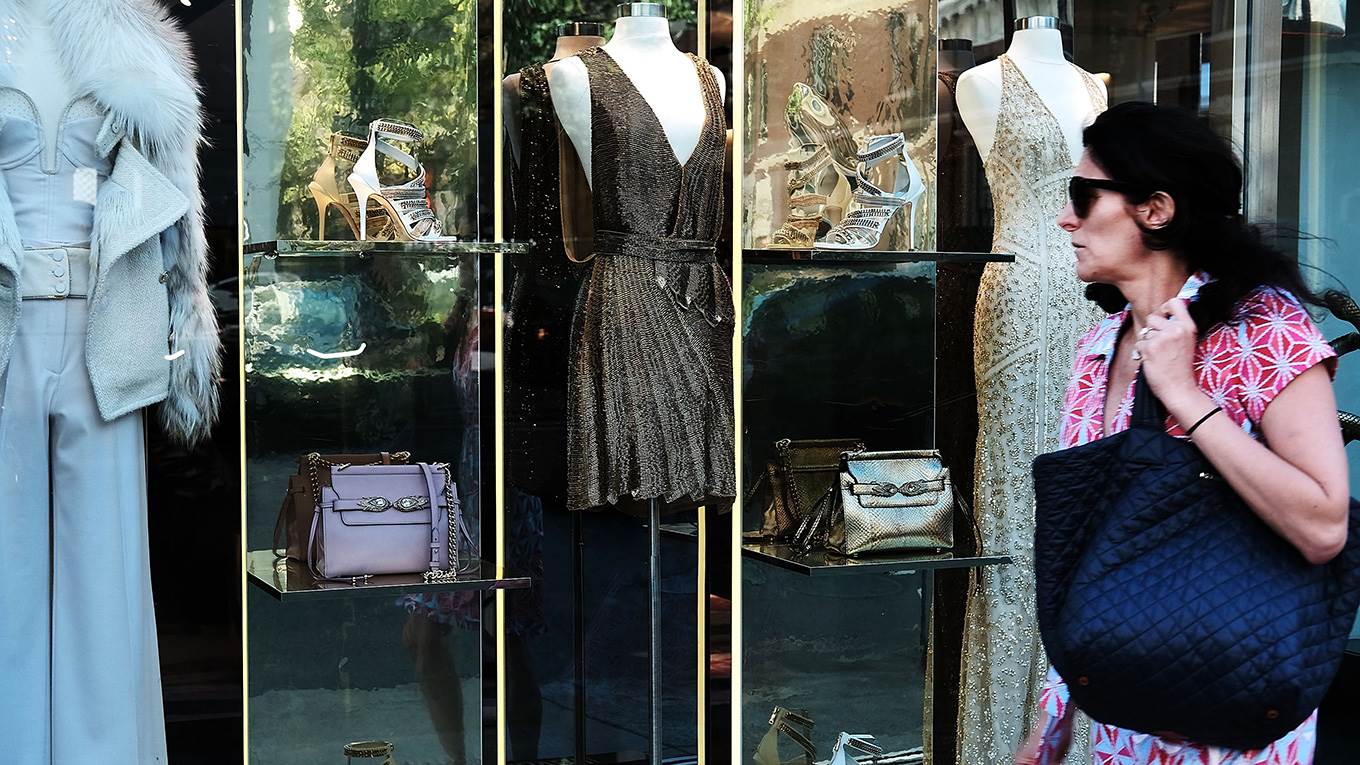 Luxury clothing is displayed in a window along Madison Avenue