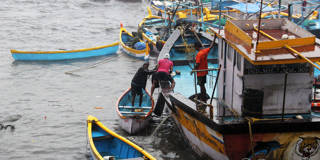 Fishermen pulling their boat out of the Sea following the cyclone ockhi