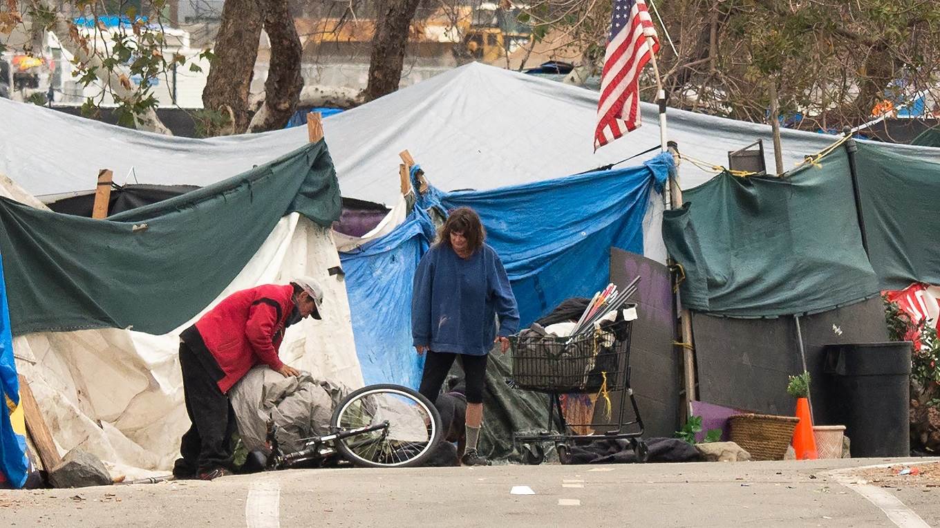A homeless encampment made of tents and tarps lines the Santa Ana