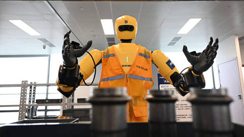 A staff member trains a humanoid robot on a simulated factory production line at a provincial embodied AI training center in Guangzhou, Guangdong Province, China, on April 7, 2026. The scene highlights the use of artificial intelligence and robotics in industrial training as Guangdong expands AI innovation and deployment across manufacturing and other sectors.