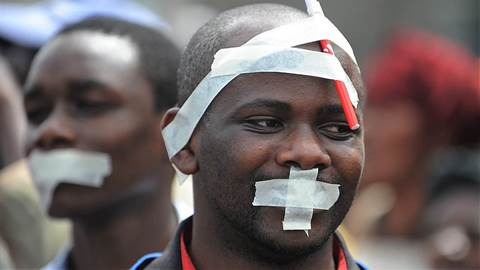 Men with tape on their faces take part in a march called by Kenyan journalists