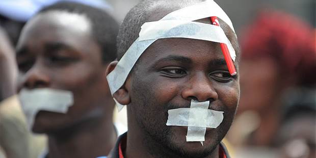 Men with tape on their faces take part in a march called by Kenyan journalists