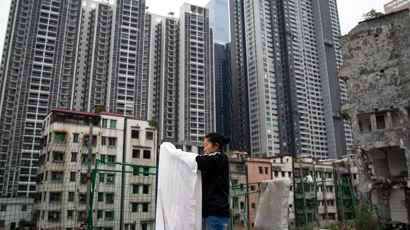A woman does laundry on the ground near demolished residential buildings 