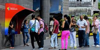 People queue to withdraw money from an ATM in Caracas 