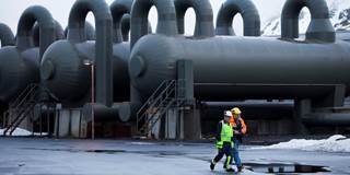 Workers walk past steam storage tanks at Reykjavik Energy's Hellisheidi Geothermal Power Plant
