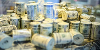 Pilas de billetes de dólar estadounidense enrollados exhibidos juntos.