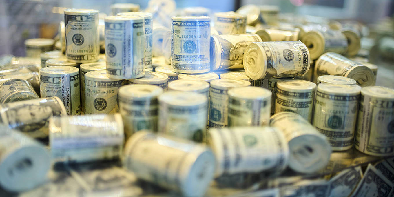 Stacks of rolled US dollar bills displayed together.