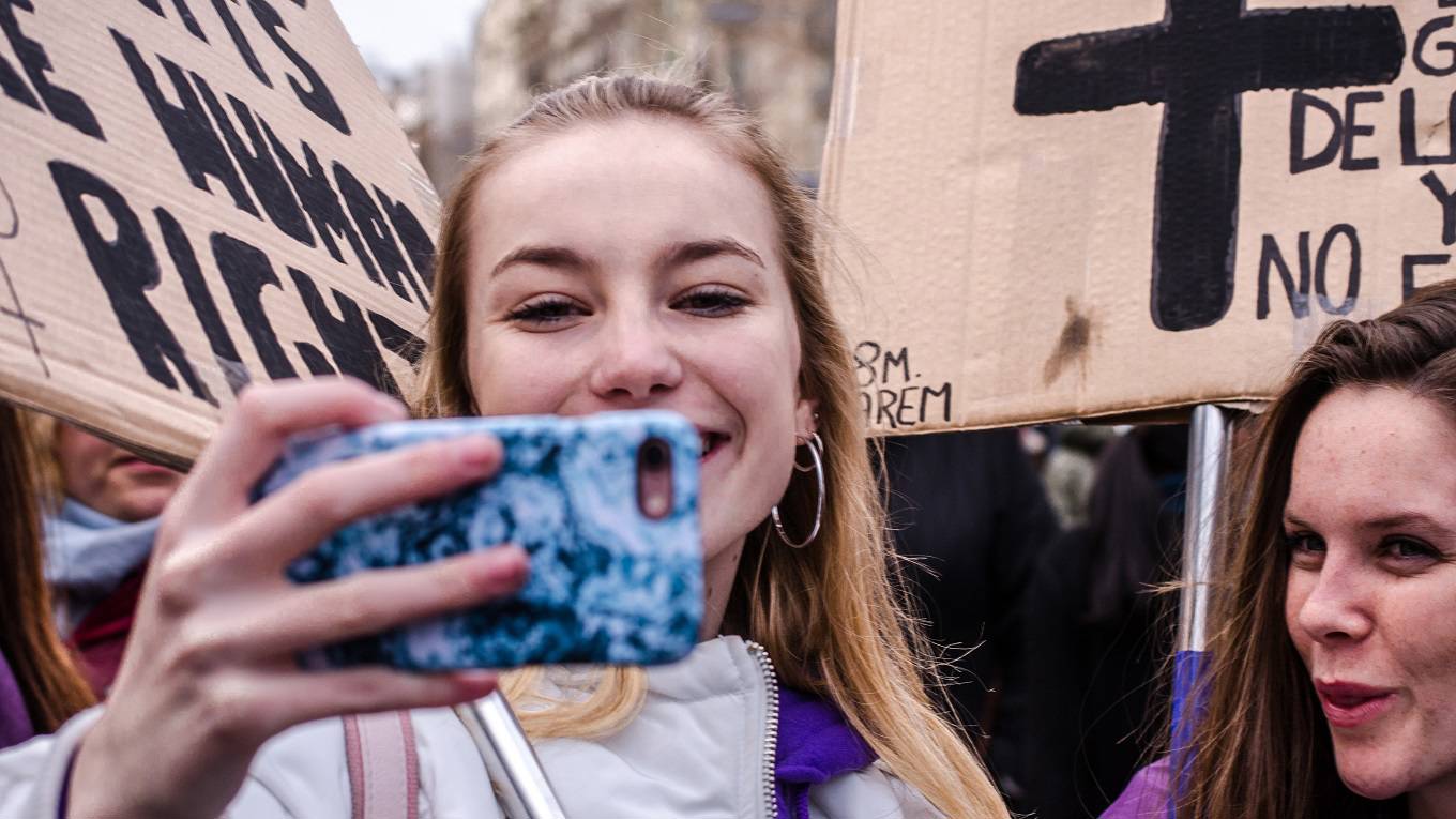  Two young girls seen taking selfies during the feminist demonstration