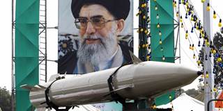 A missile stands on display in front of a large portrait of Iran's Supreme Leader Ayatollah Ali Khamenei
