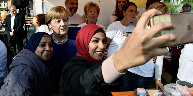 A syrian refugee poses for a selfie photo with Angela Merkel