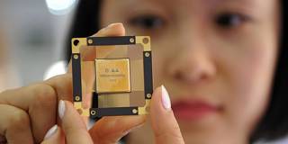A worker presents a chip for fifth-generation (5G) mobile networks at China Electronics Technology Group
