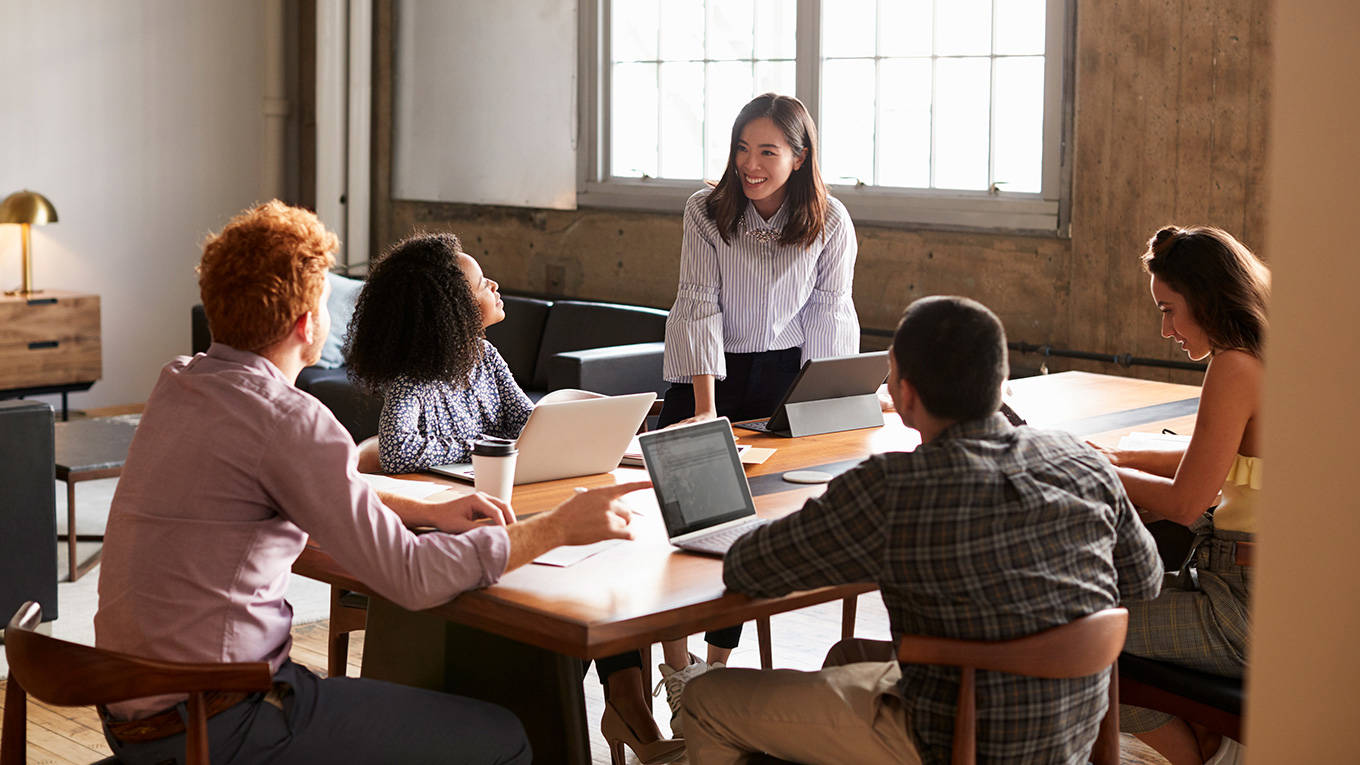 Woman standing to address colleagues at a work meeting
