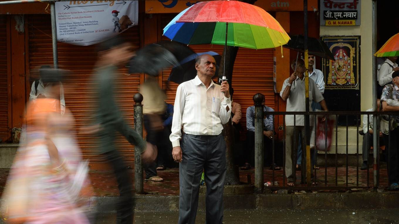 An onlooker watches share prices on a digital broadcast on the facade of the Bombay Stock Exchange