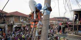 A volunteer sets up a street lamp in the market area of the Oshodi district in Lagos