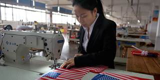 A Chinese employee makes US national flags