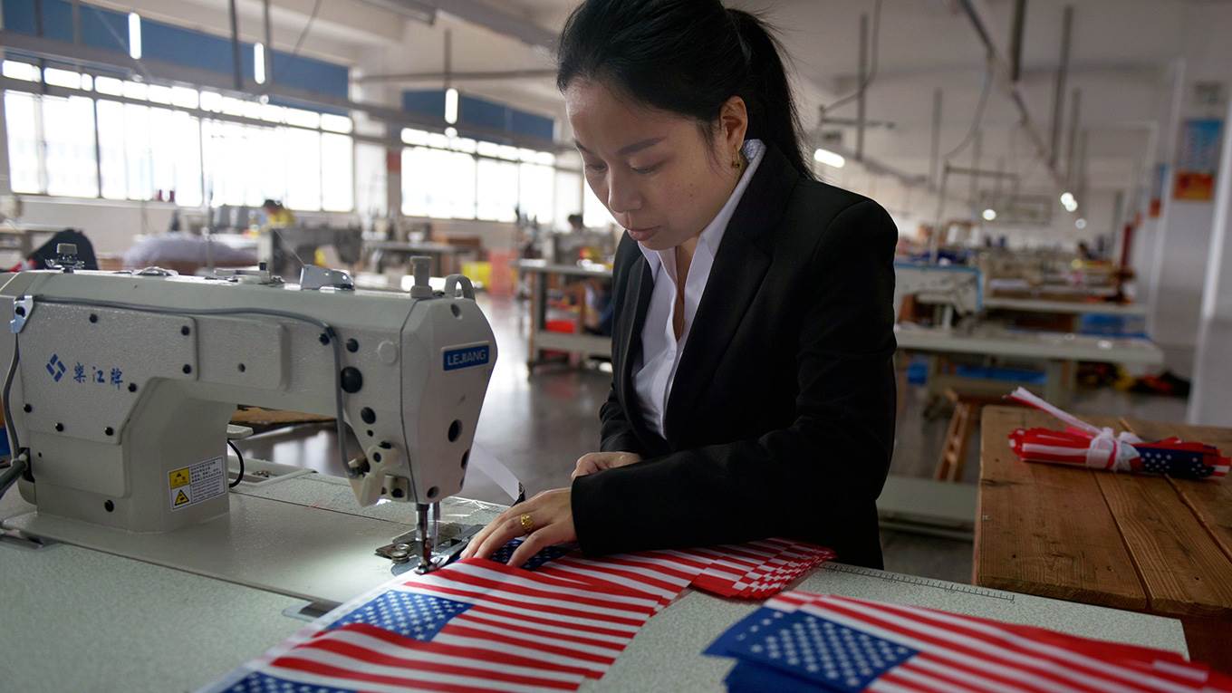 A Chinese employee makes US national flags