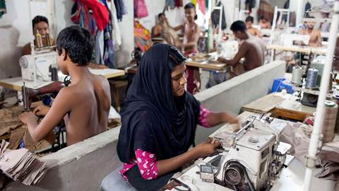 A woman sews a cloth in a local garment shop in Dhaka