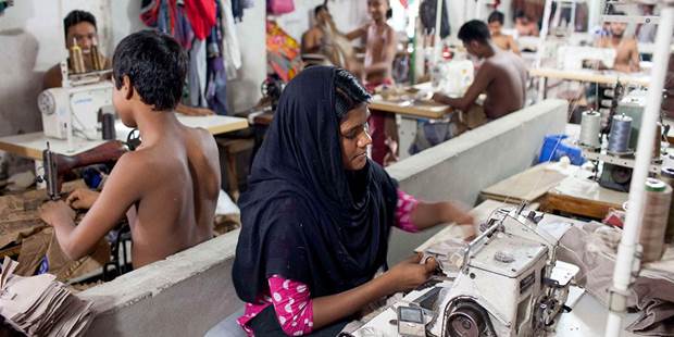 A woman sews a cloth in a local garment shop in Dhaka