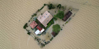 Aerial view of an isolated house surrounded by floodwater during a king tide on a low-lying island.