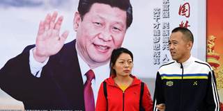 People walk past a poster of Chinese President Xi Jinping 