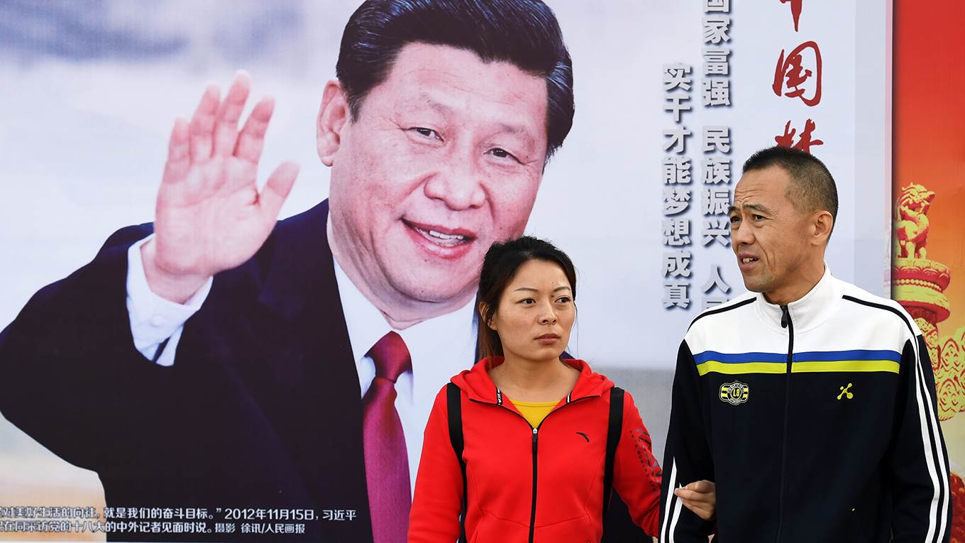 People walk past a poster of Chinese President Xi Jinping