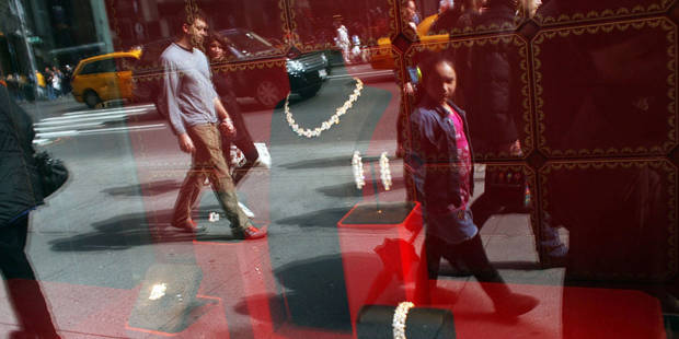 Pedestrians look at diamonds in a window display along 5th Avenue