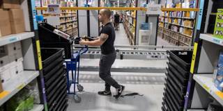 A worker pushes a trolley as he walks between goods stored inside an Amazon.co.uk fulfillment centre